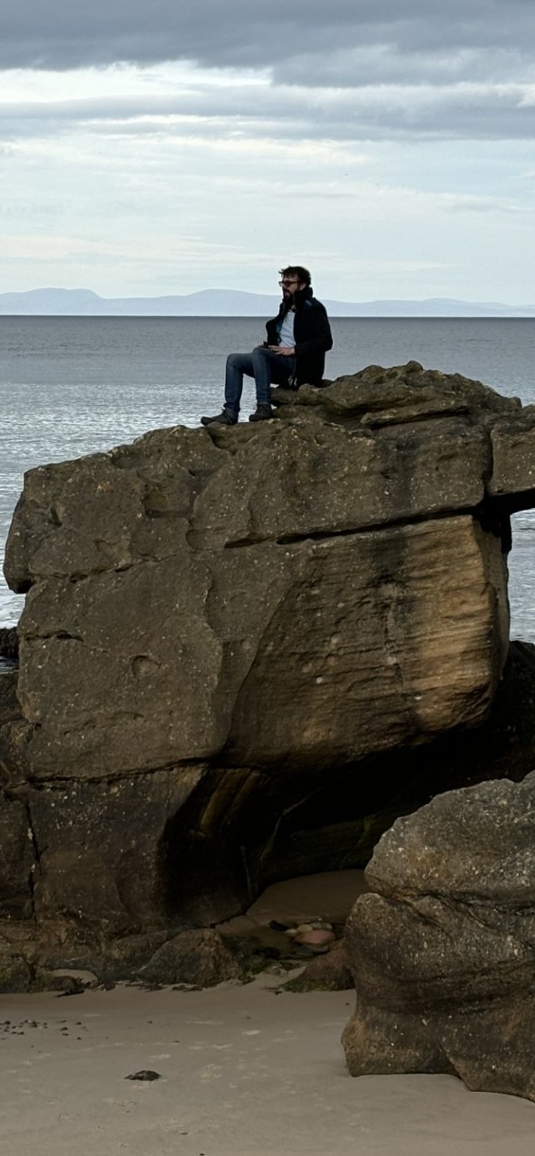Male sitting on a cliff admiring the view of the sea