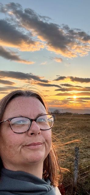 Woman smiling with a sunset backdrop in the countryside